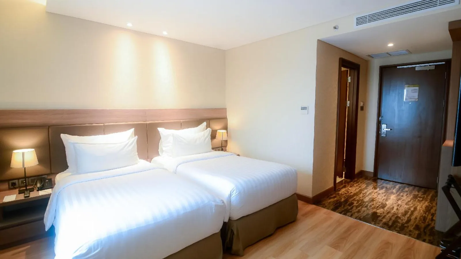 Twin bedroom at The Excelton Hotel Palembang with two single beds and curtain-covered window