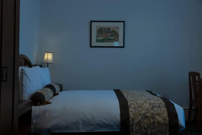 A cozy bed setup in a room at The Fujiya Hotel in Hakone, showcasing its decorative style.