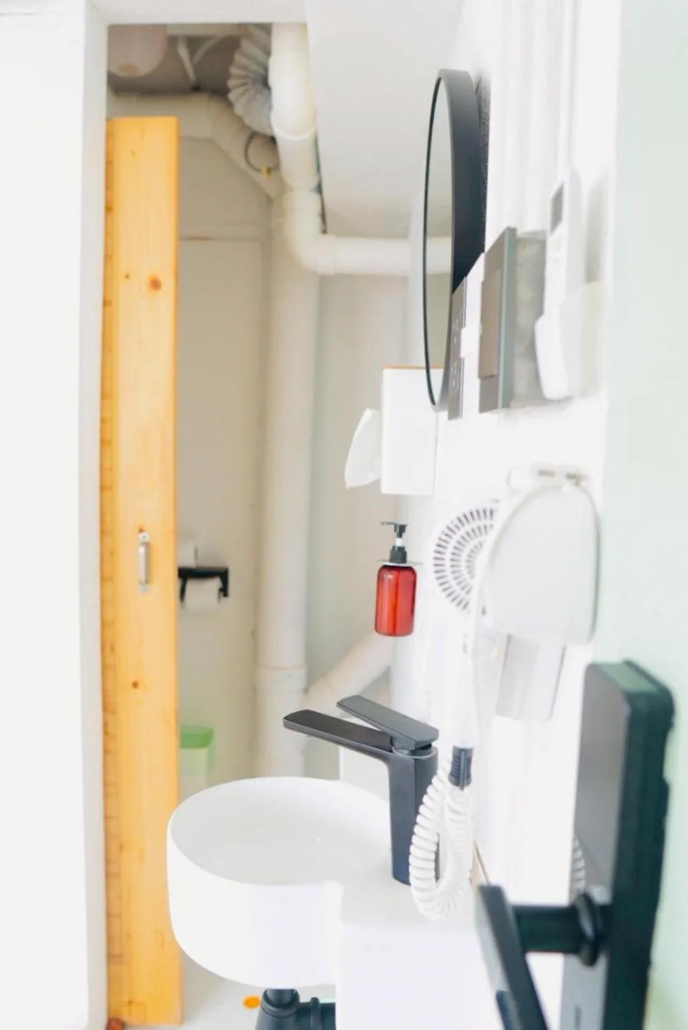 Bathroom detail at The Green Khaosan Bangkok showing sink, mirror, hair dryer, and toiletries