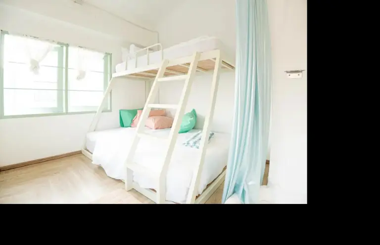 Bright bunk room at The Green Khaosan Bangkok with white bunk bed, pastel pillows, and natural light