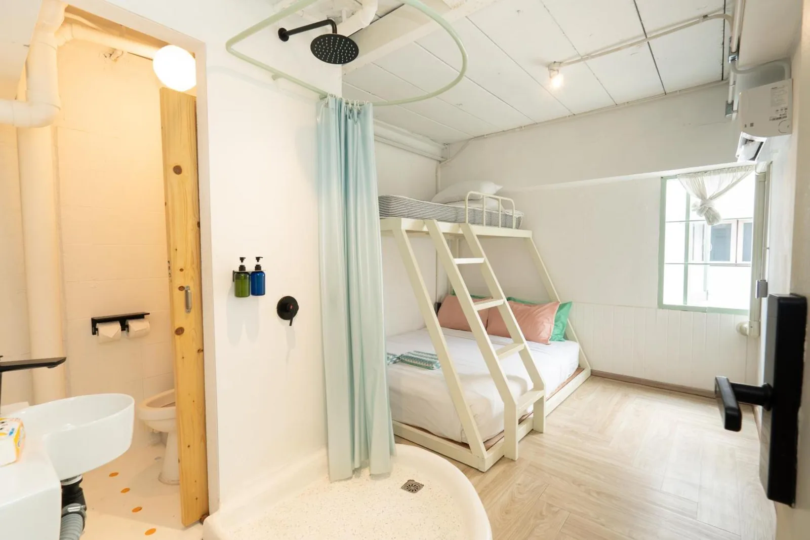 Bright bunk room at The Green Khaosan Bangkok with white bunk bed, pastel pillows, and natural light