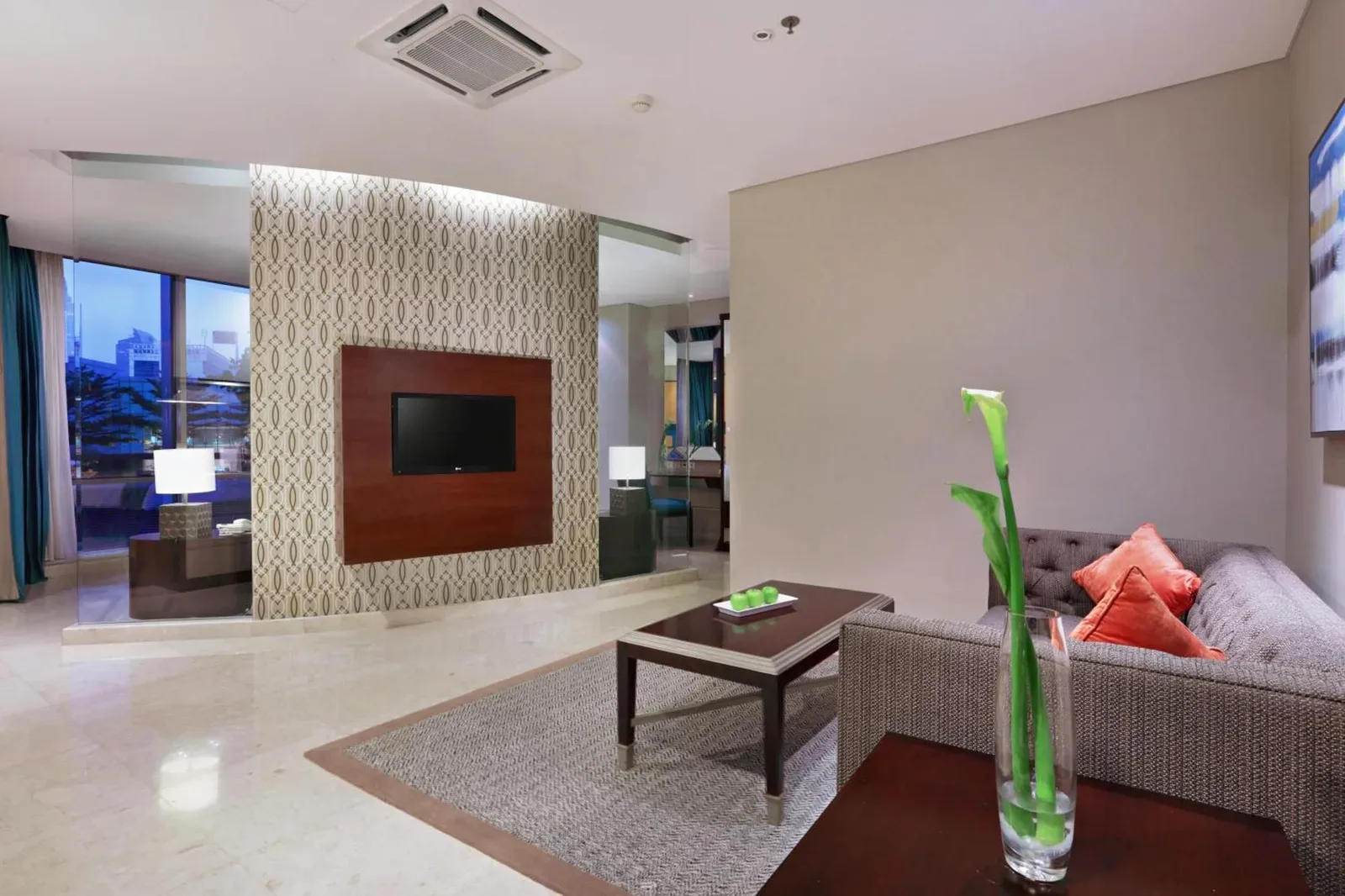 The Grove Suites by Grand Aston Jakarta living room with sofa, TV wall, and modern apartment-style seating
