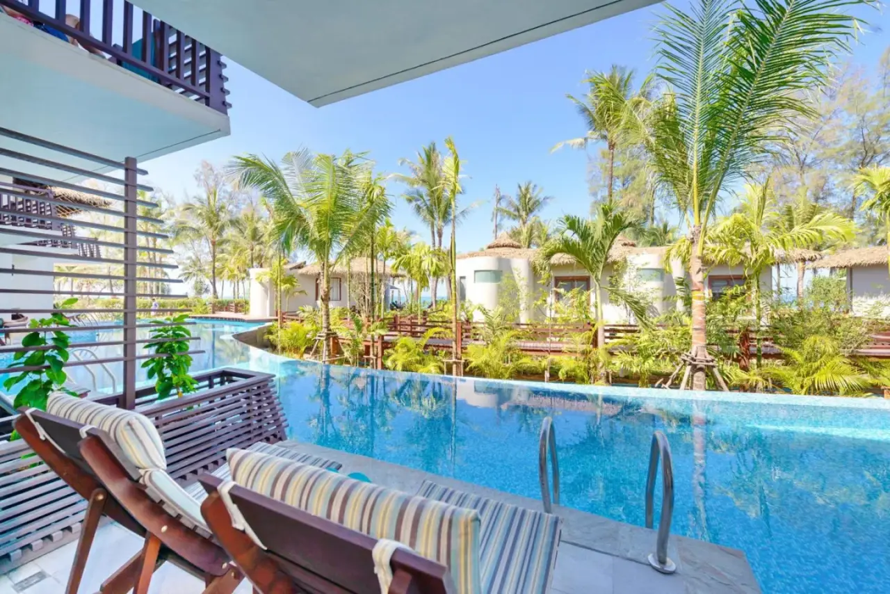 Pool loungers at The Haven Khao Lak in Khao Lak overlooking a tropical swimming pool and gardens.