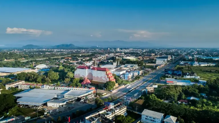Vista aérea de la ciudad alrededor de The Heritage Chiang Rai Hotel and Convention mostrando el hotel, las carreteras y el paisaje de Chiang Rai.