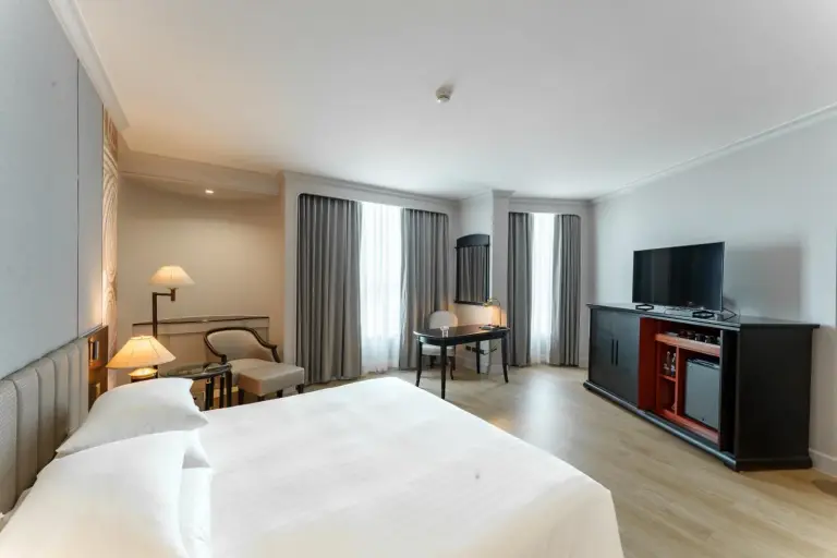 Modernes Schlafzimmer im The Heritage Grand Khon Kaen Hotel and Convention in Khon Kaen mit TV-Schrank, Vorhängen und minimalistischer Einrichtung.