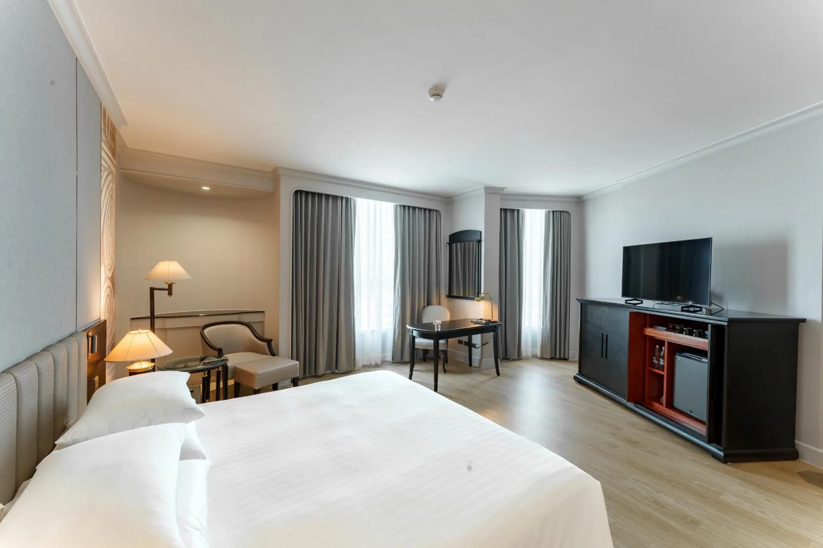 Modernes Schlafzimmer im The Heritage Grand Khon Kaen Hotel and Convention in Khon Kaen mit TV-Schrank, Vorhängen und minimalistischer Einrichtung.