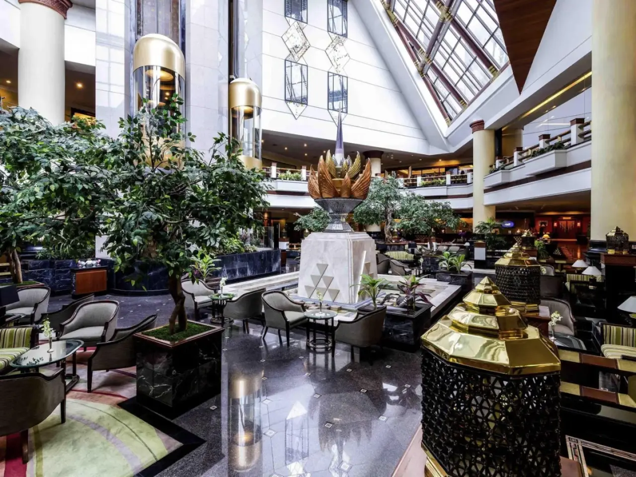 Lobbyatrium im The Heritage Grand Khon Kaen Hotel and Convention in Khon Kaen mit modernen Sitzgelegenheiten, Innenbegrünung und einem großzügigen, von Oberlichtern erhellten Innenraum.