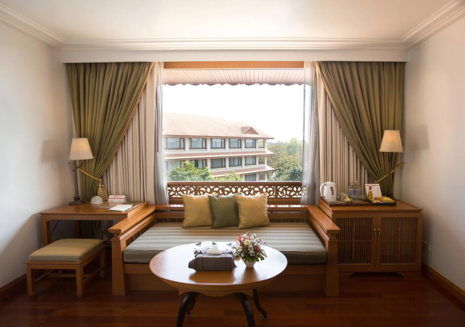 Zona de asientos junto a la ventana en The Imperial River House Resort, Chiang Rai con vistas a los jardines del resort