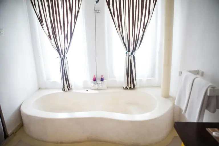 Spacious bathroom at The Mansion Resort Hotel & Spa in Ubud with a freestanding bathtub and striped curtains