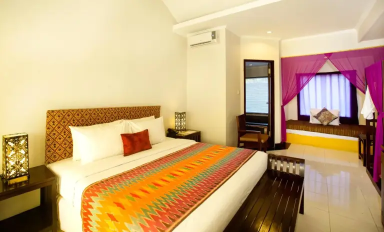 King bedroom at The Mansion Resort Hotel & Spa in Ubud with colorful textile accents and a daybed