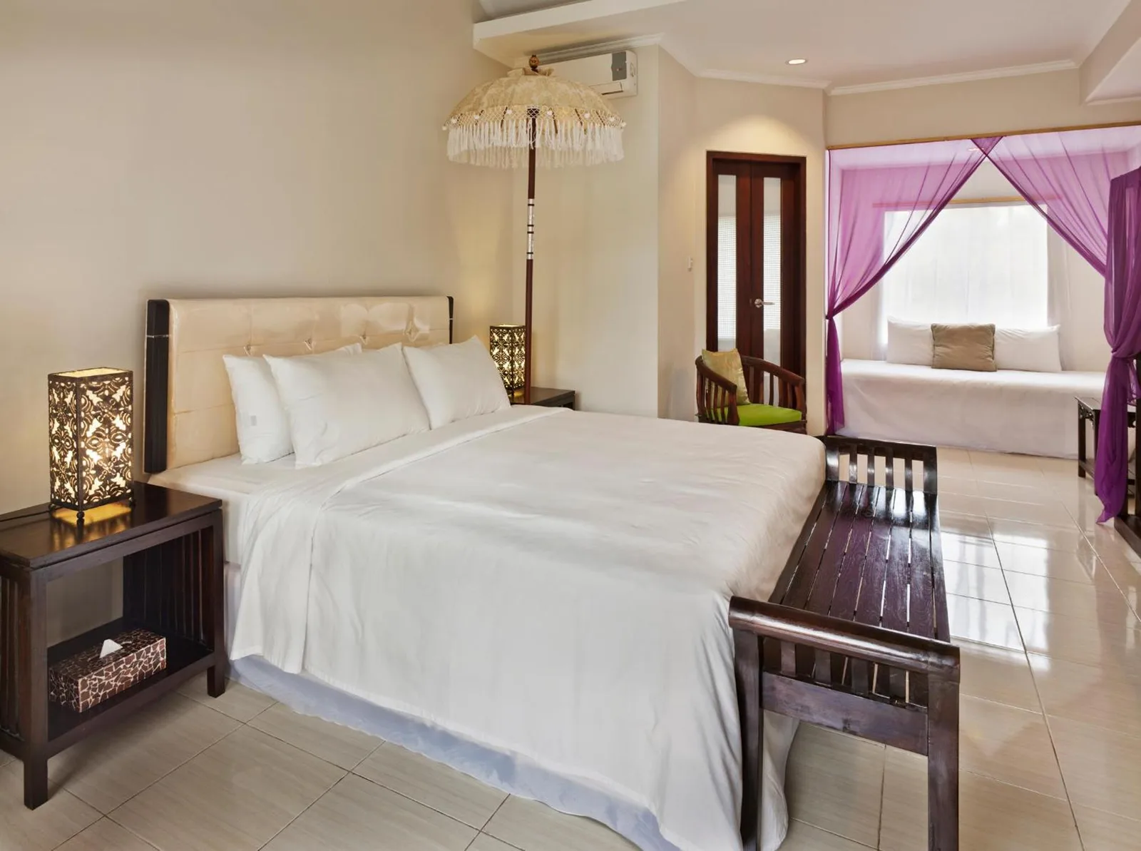 Elegant suite bedroom at The Mansion Resort Hotel & Spa in Ubud with a canopy bed and purple drapes