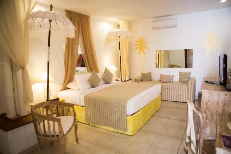 Stylish suite room at The Mansion Resort Hotel & Spa in Ubud with canopy bed, sofa, and tropical decor