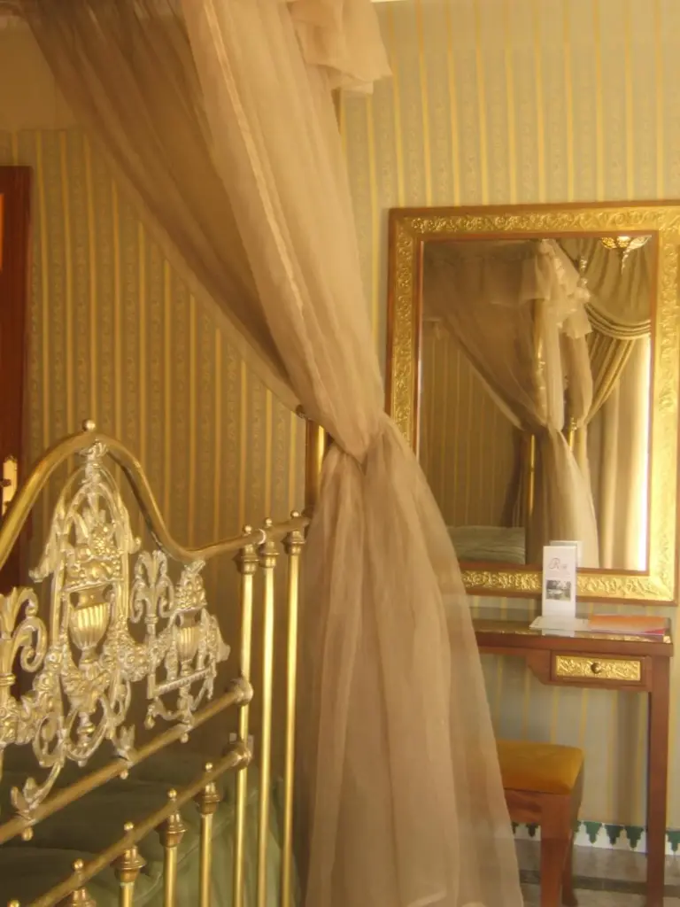 The Red House Marrakech elegant bedroom with golden decor and mirror