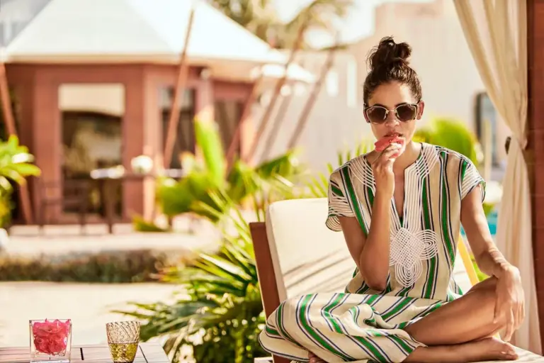 Huésped relajándose junto a la piscina en The Ritz-Carlton Ras Al Khaimah, Al Hamra Beach