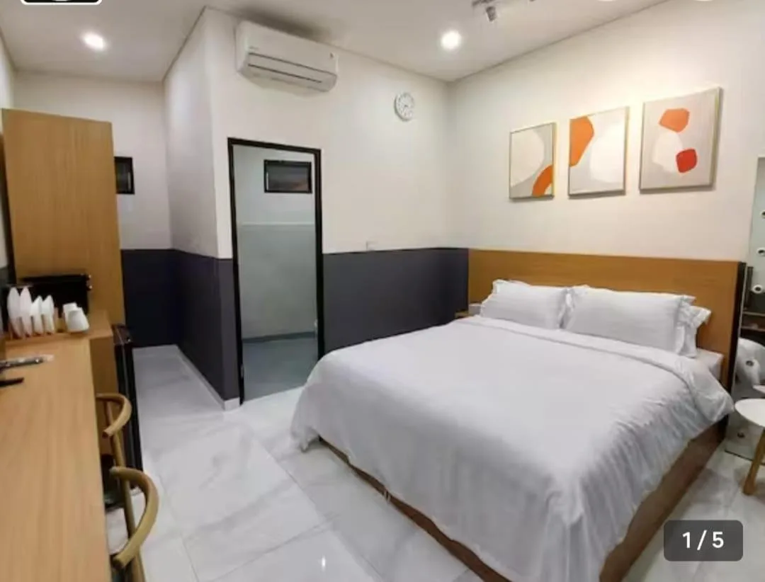 Dormitorio en The W Residence Jakarta con una cama doble, arte en la pared y mobiliario minimalista.