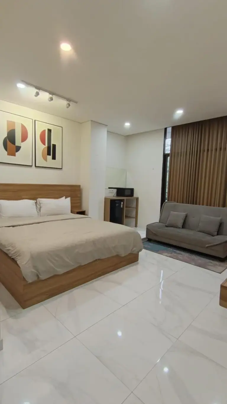 Amplia suite dormitorio en The W Residence Jakarta con una cama grande y zona de estar.