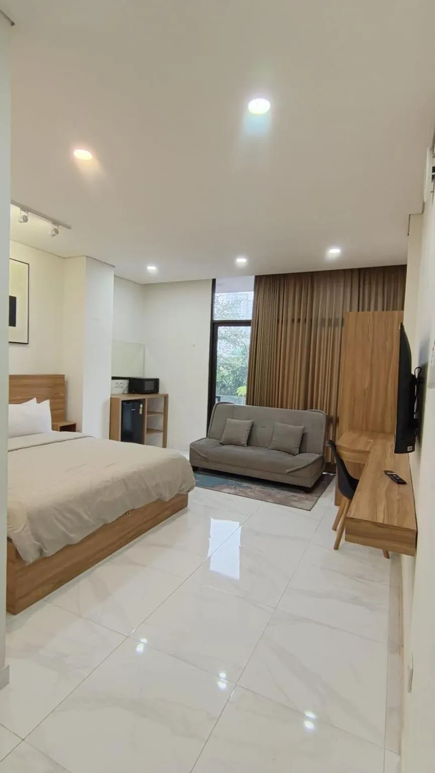 Habitación estudio en The W Residence Jakarta con una cama, un sofá, un escritorio y vistas desde la ventana.