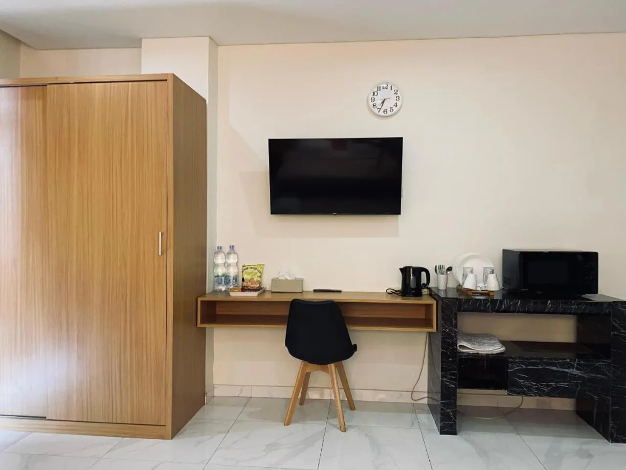 Zona de trabajo y rincón multimedia en The W Residence Jakarta con escritorio, TV, armario y minibar.
