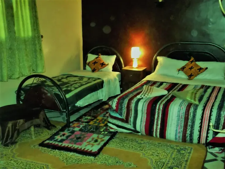 Interior de una habitación twin en Tifinagh Guest House en Merzouga con dos camas e iluminación cálida