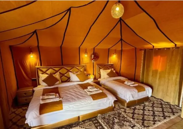 Tinariwen Luxury Camp – Merzouga, Morocco hotel – a bedroom with two beds with towels on it at Tinariwen Luxury Camp in Merzouga