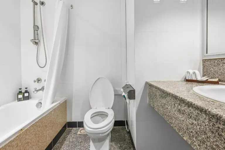 Salle de bains du Town in Town Hotel Bangkok avec baignoire, douche, toilettes et vasque en granit