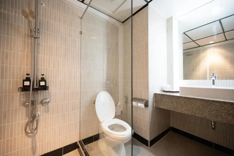 Salle de bains du Town in Town Hotel Bangkok avec douche vitrée, toilettes et lavabo avec meuble