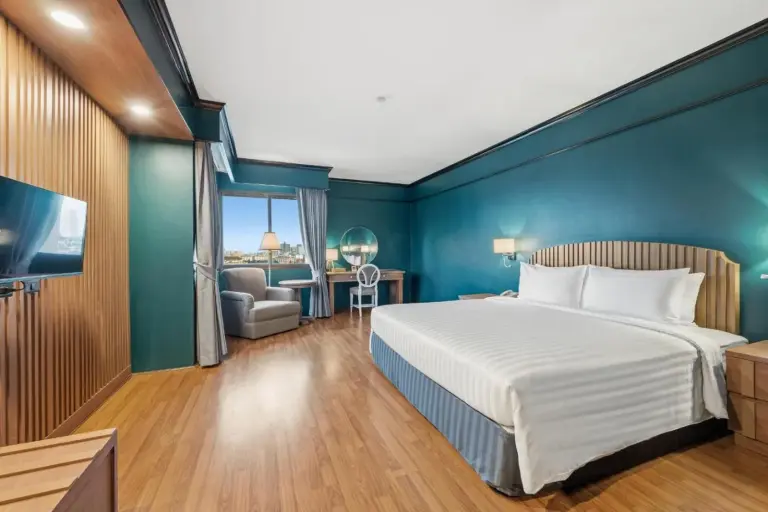 Chambre de suite du Town in Town Hotel Bangkok avec lit king-size, fauteuil de salon et espace de travail
