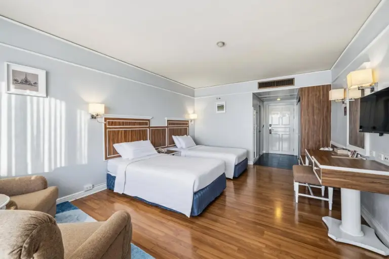 Chambre twin du Town in Town Hotel Bangkok avec deux lits simples, bureau et fauteuil