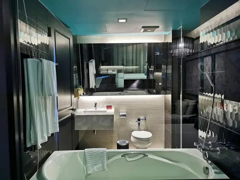 Baño de TSix5 Quarter Pattaya con bañera, ducha separada y tocador moderno