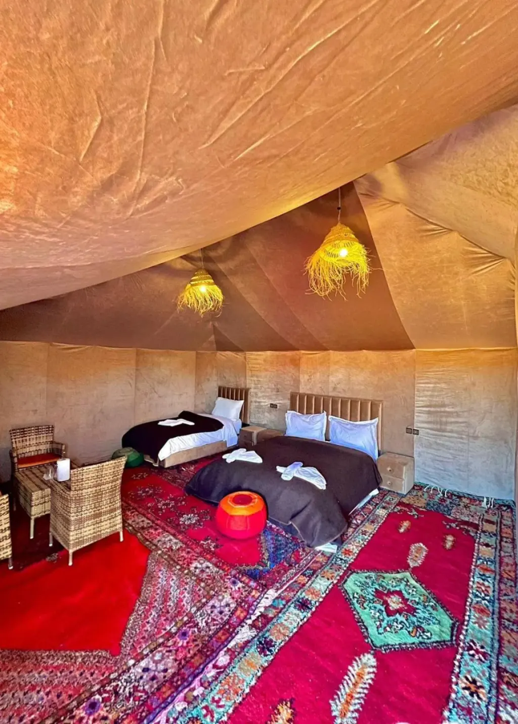 Four bed guest tent at Tudert Luxury Camp in Merzouga with red rugs and woven light fixtures