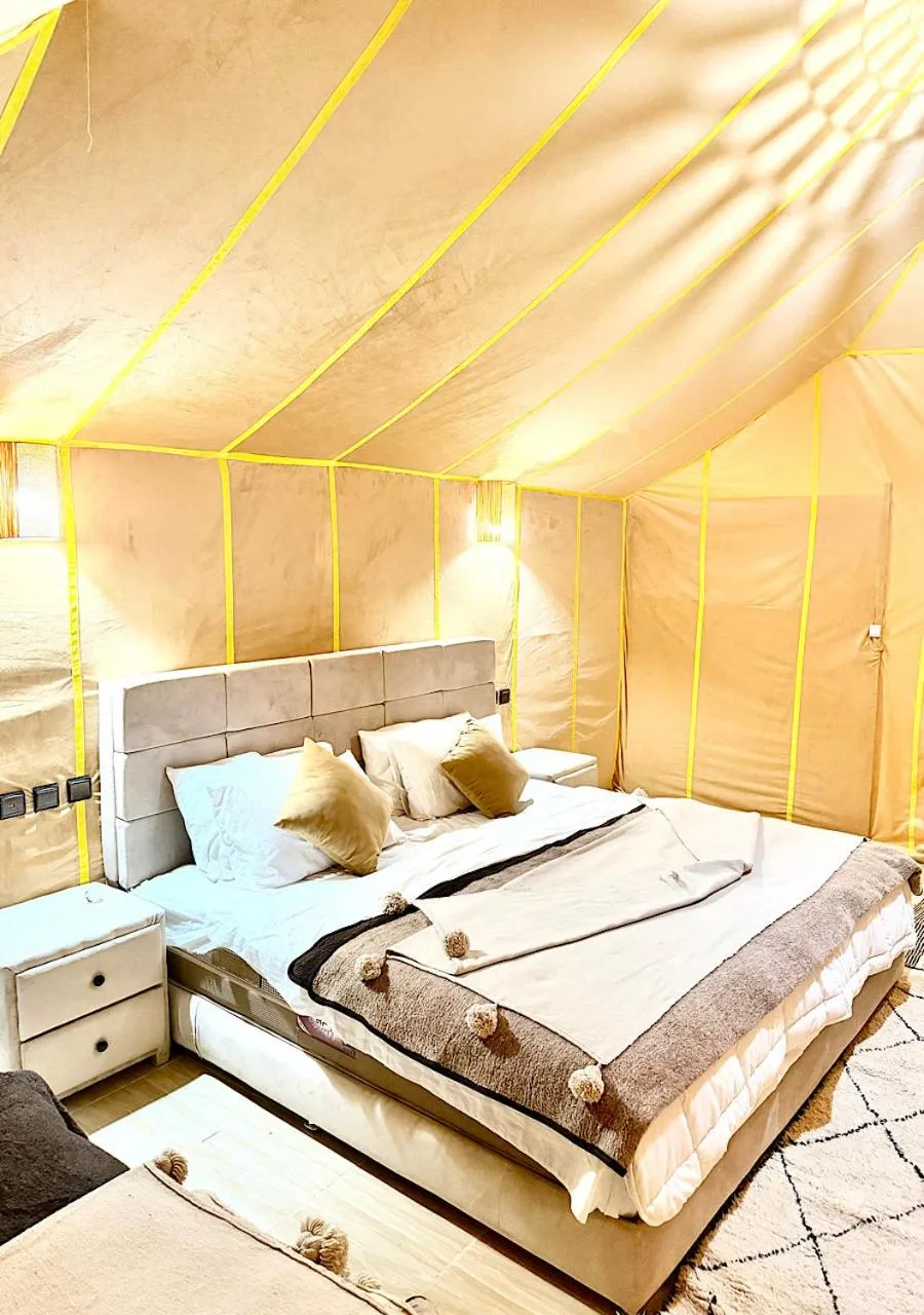 Suite de lujo luminosa en Ultimate Luxury Camp en Merzouga con una cama grande y un interior de tienda beige