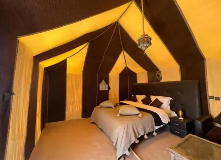 Amplio interior de suite de lujo en Ultimate Luxury Camp en Merzouga con una cama king y luz suave