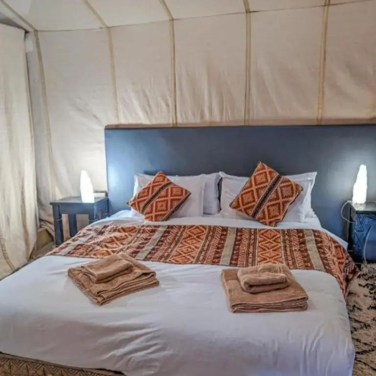 Luxury tent suite at Unique Sahara Camp in Merzouga with a king bed and patterned pillows