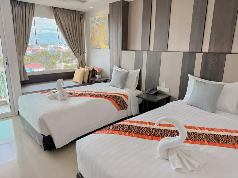 Zweibettzimmer im Vareena Palace Hotel in Pattaya mit zwei Einzelbetten, Blick aus dem Fenster und dekorativen Kissen.