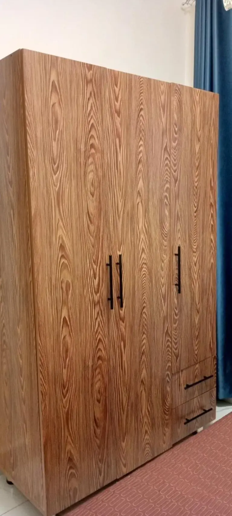 Holzkleiderschrank im VENUS APARTMENT Kigali in Nyamata mit hohen Türen und Schubladenfächern.