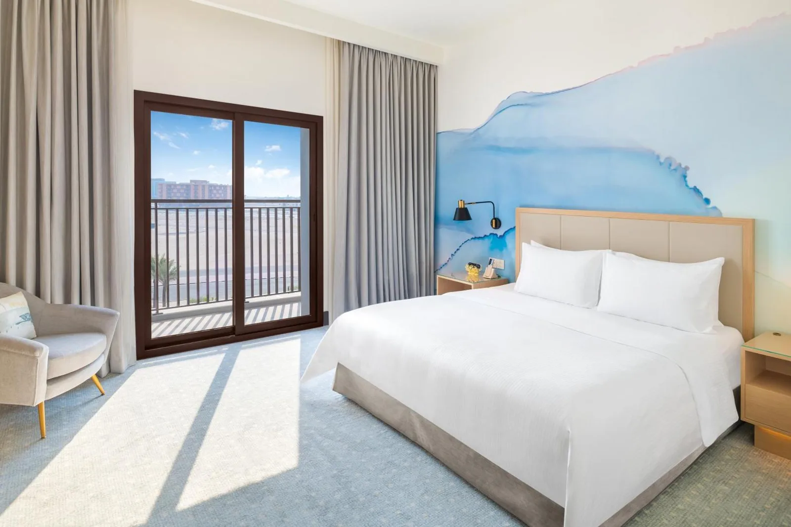 Bright king room at Vida Beach Resort Umm Al Quwain with ocean-inspired decor and balcony view