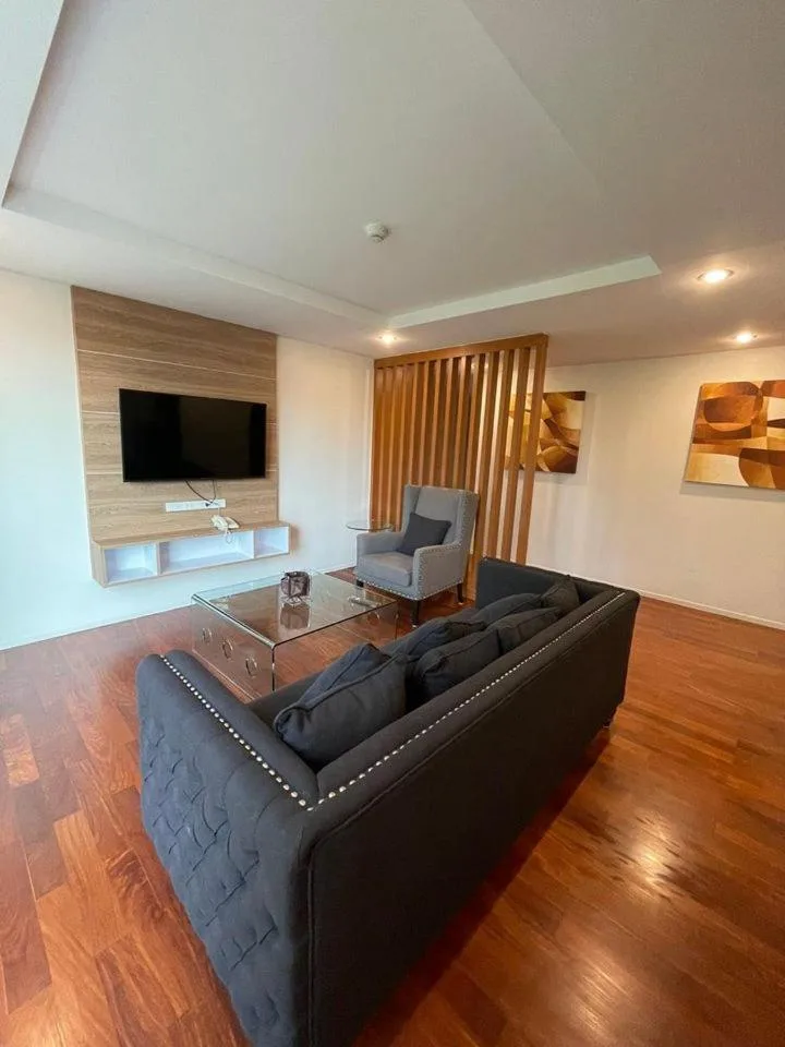Salón en el hotel ViVi Avenue Thonglor en Bangkok con televisor montado en la pared y sillón