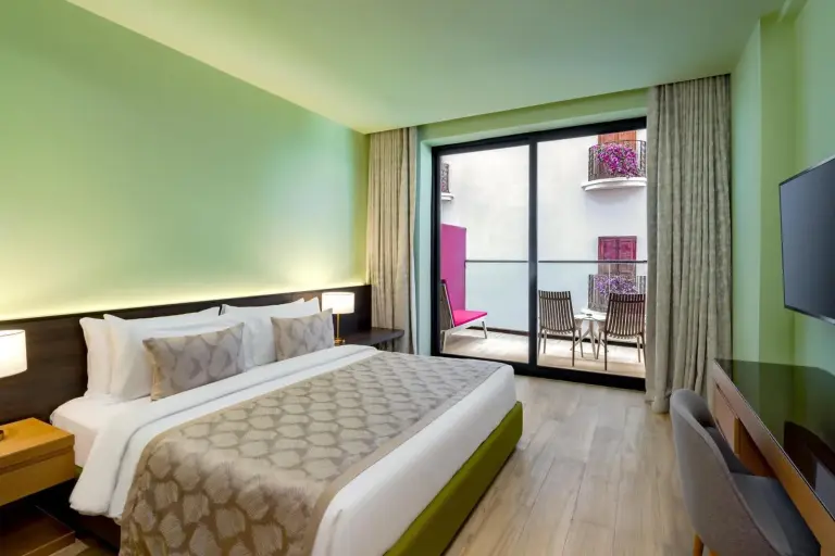 Helles Gästezimmer mit Zugang zum Balkon im voco Dubai Monaco, The Heart of Europe by IHG-Adult only in Dubai.
