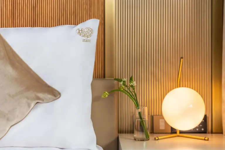 Nahaufnahme eines Marken-Kissens und einer Nachttischlampe in einem Zimmer im voco Dubai Monaco, The Heart of Europe by IHG-Adult only in Dubai.