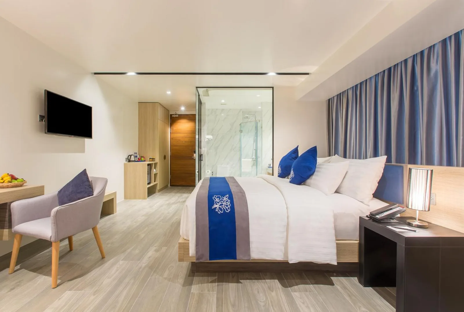 Habitación Deluxe en Wintree City Resort Chiang Mai con una cama king, escritorio, sillón y baño al fondo.