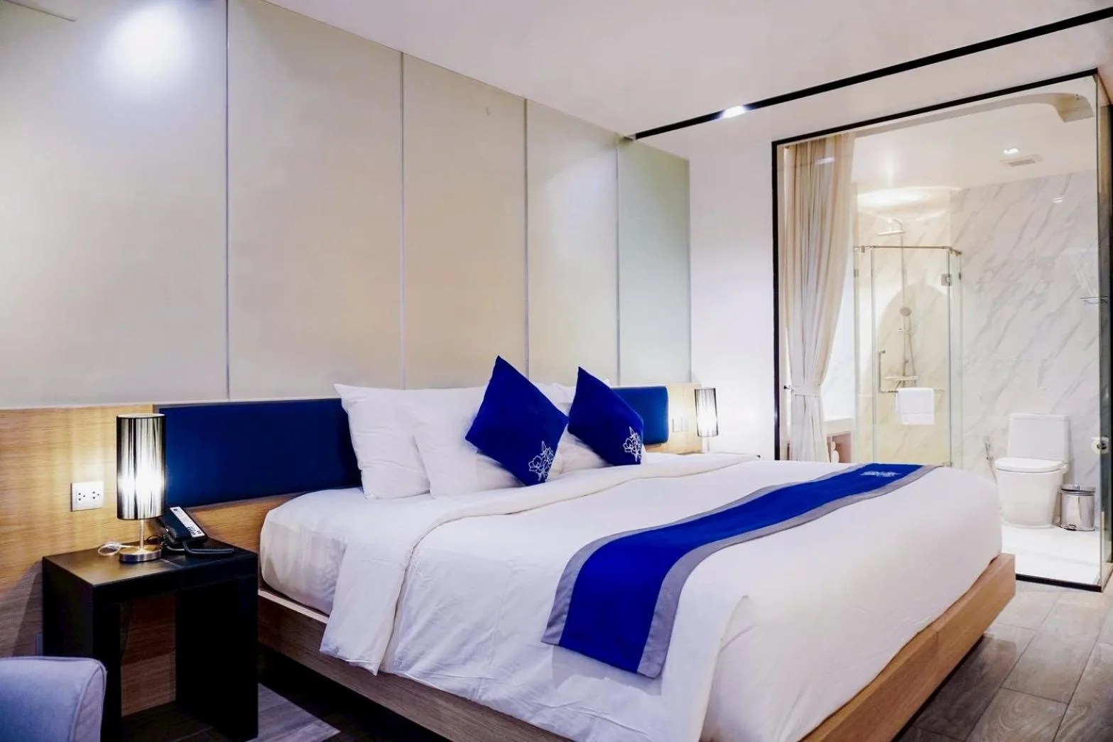 Habitación de huéspedes en Wintree City Resort Chiang Mai con una cama king, mesitas de noche y una puerta abierta al baño.