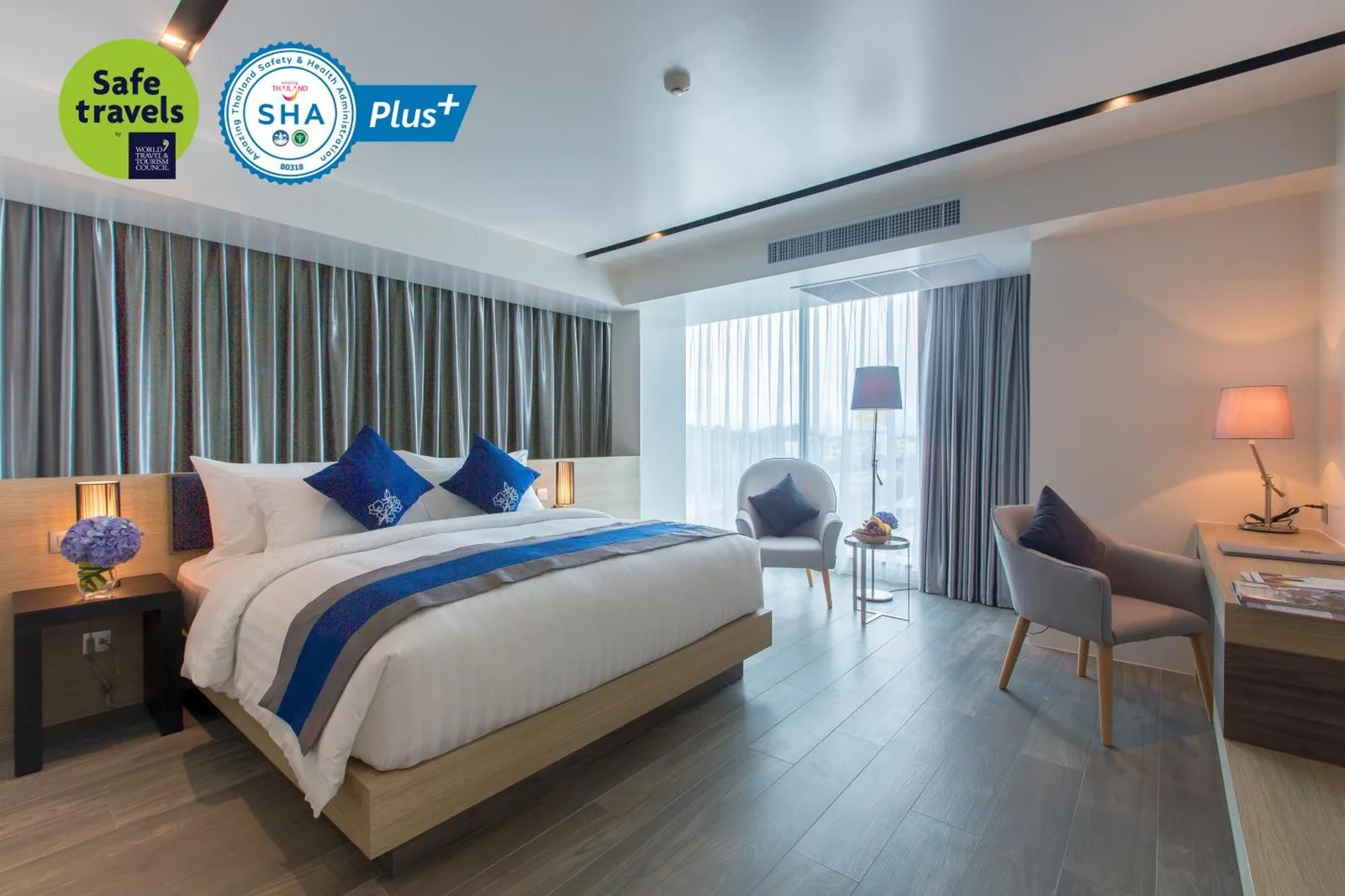 Habitación Superior en Wintree City Resort Chiang Mai con una cama king, zona de estar, escritorio y pared de cortinas.
