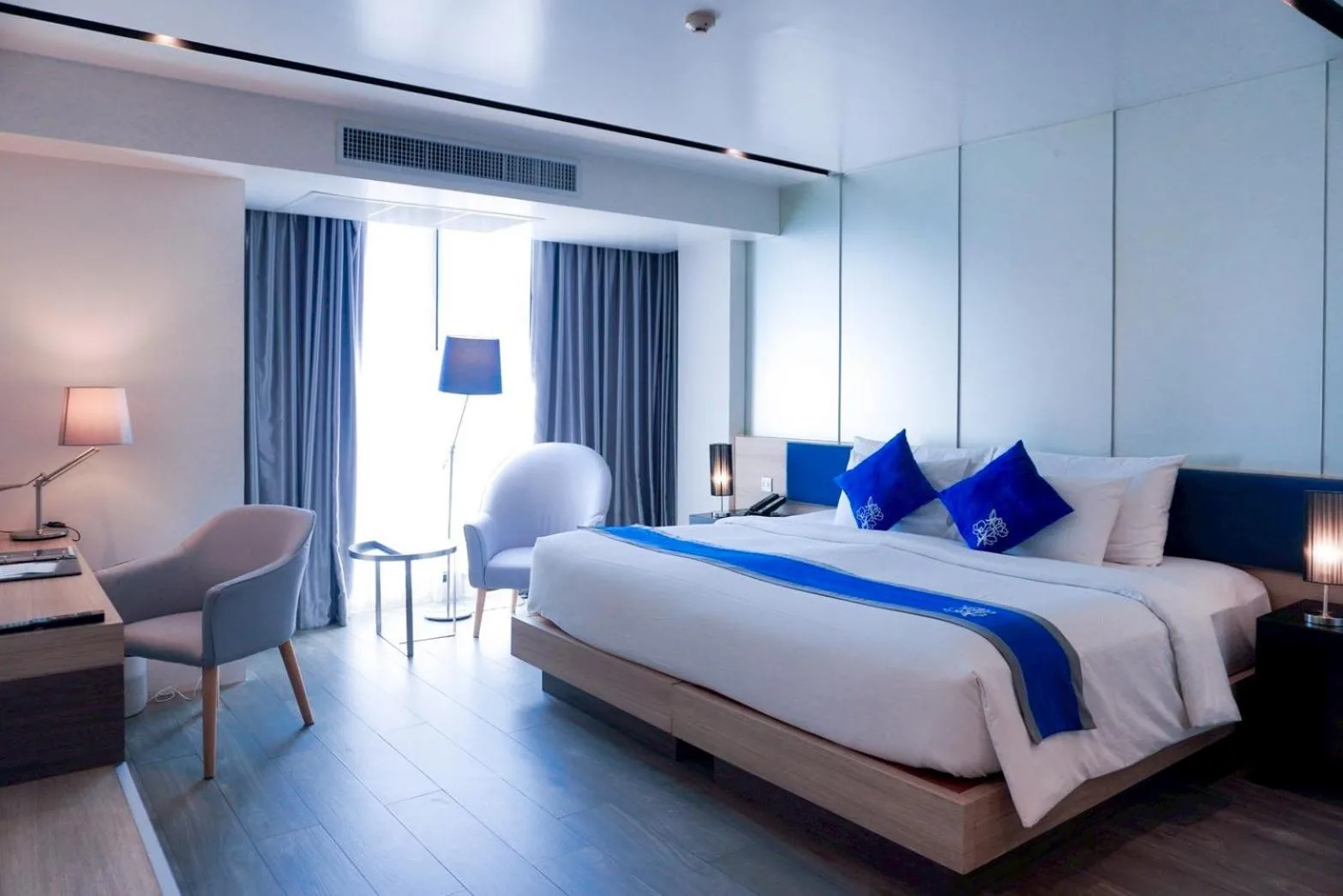 Habitación Superior en Wintree City Resort Chiang Mai con una cama king, escritorio, sillón y luz en el balcón.