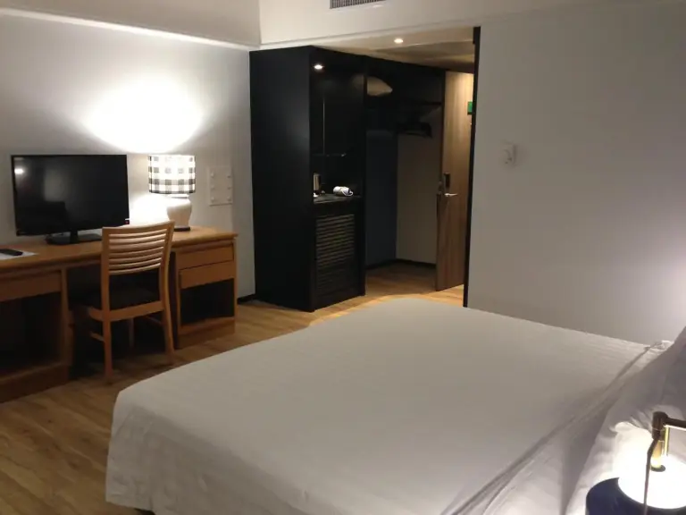 Schreibtisch- und Kleiderschrankbereich im Gästezimmer des Hotels Witz Bangkok Ramkhamhaeng in Bangkok mit TV und Kleiderschrank