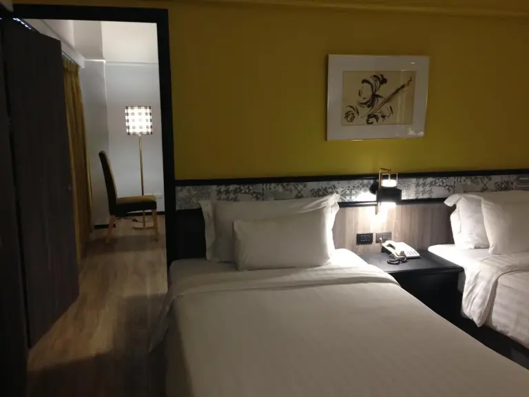 Gelbes Zweibettzimmer im Hotel Witz Bangkok Ramkhamhaeng in Bangkok mit Betten und Sitzbereich im Flur