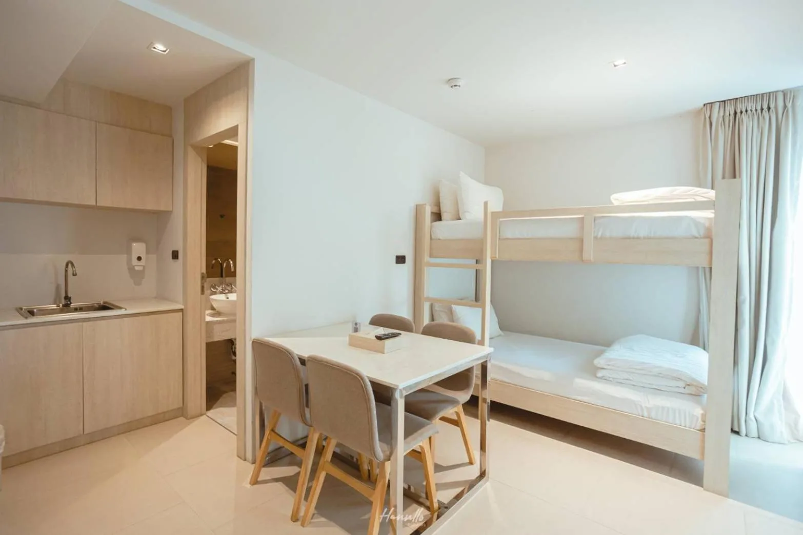 Worita Cove Hotel – Pattaya, Thailand hotel – a room with bunk beds and a table and a kitchen at Worita Cove Hotel in Na Jomtien