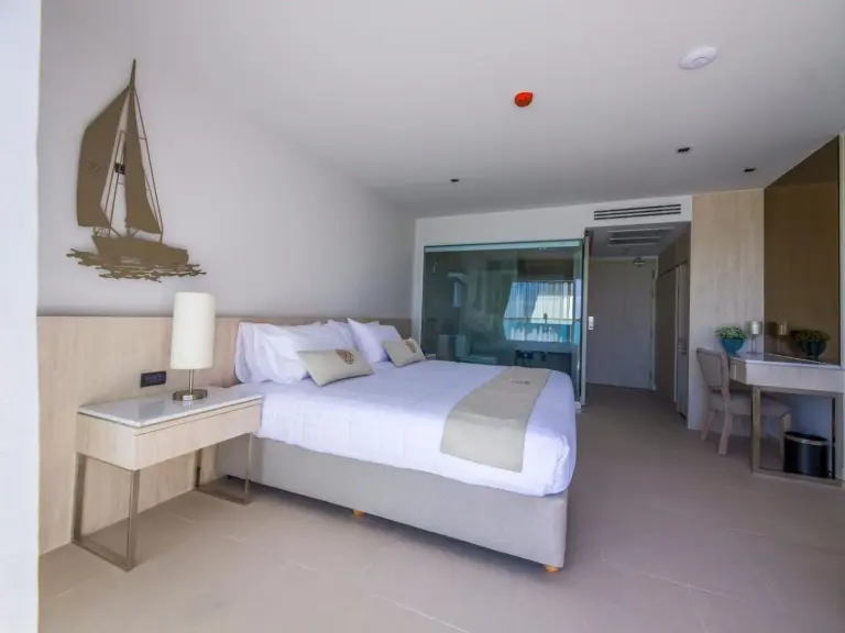 King bedroom at Worita Cove Hotel in Pattaya with sailboat wall decor, work desk, and balcony access.