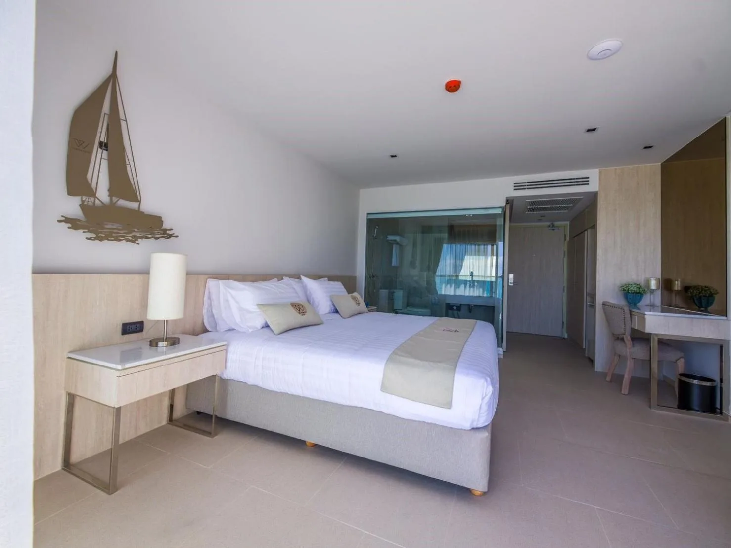 King bedroom at Worita Cove Hotel in Pattaya with sailboat wall decor, work desk, and balcony access.