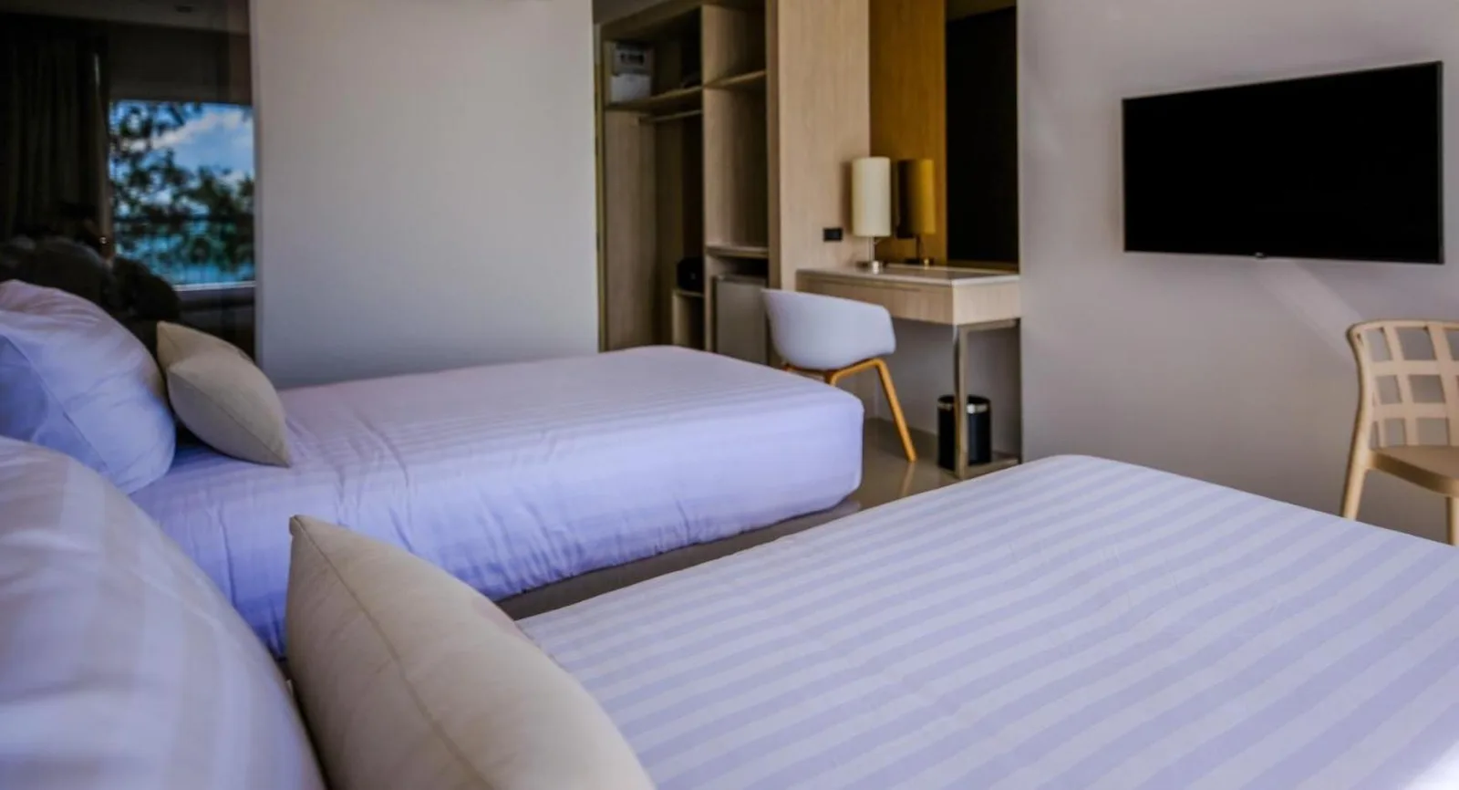 Twin guest room interior at Worita Cove Hotel Pattaya with beds, desk, and wall-mounted TV.