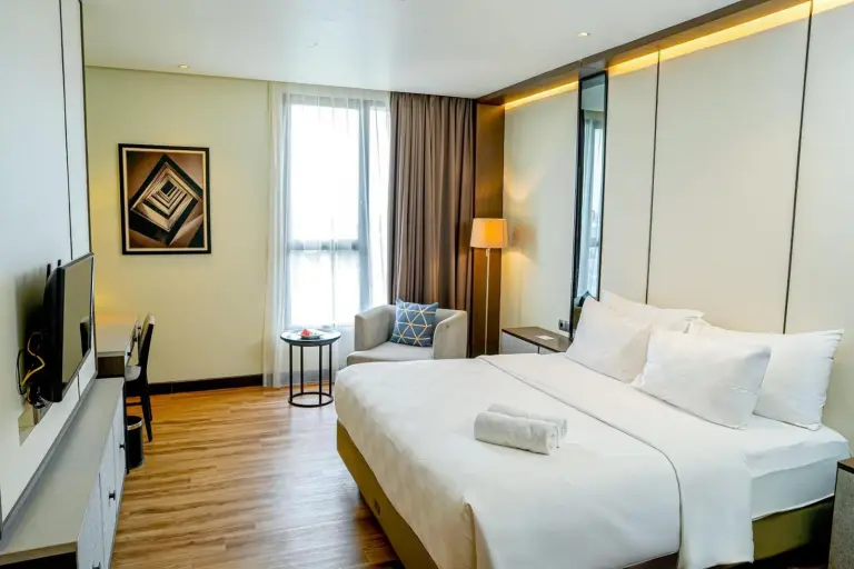 Habitación estándar en Wyndham Opi Hotel Palembang con cama king, suelo de madera y rincón de estar
